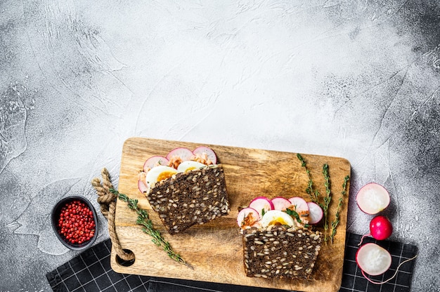 Grain bread sandwiches with hot smoked salmon, eggs and radishes. Healthy balanced food. Gray background, top view, space for text