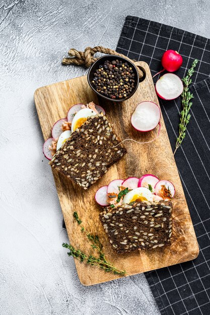 Grain bread sandwiches with hot smoked salmon, eggs and radishes. Healthy balanced food., top view.