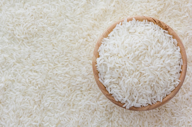 Grains of Thai jasmine rice in wooden bowl on white rice background