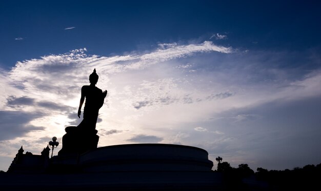 Grand walking buddha bronze statue in Phutthamonthon Buddhist province Thailand in twilight sky