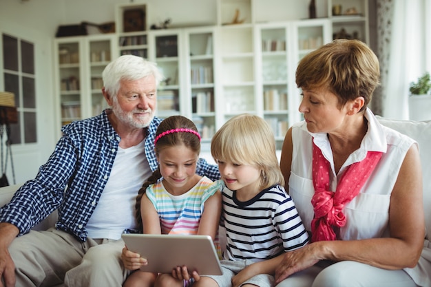 Grandchildren using digital tablet with their grandparents