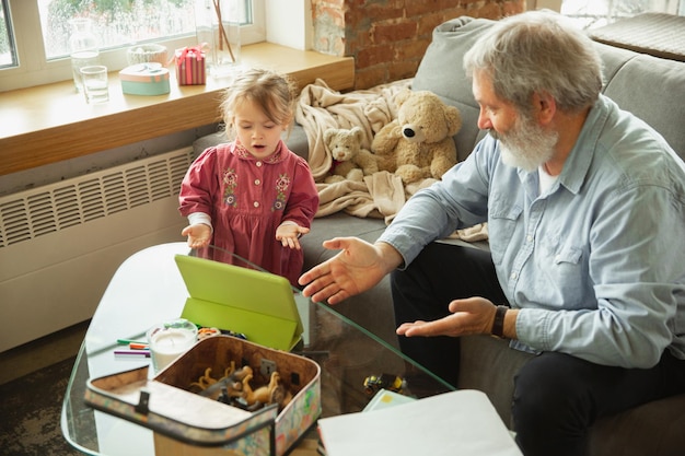 Grandfather and child playing together at home. Happiness, family, relathionship, education concept.