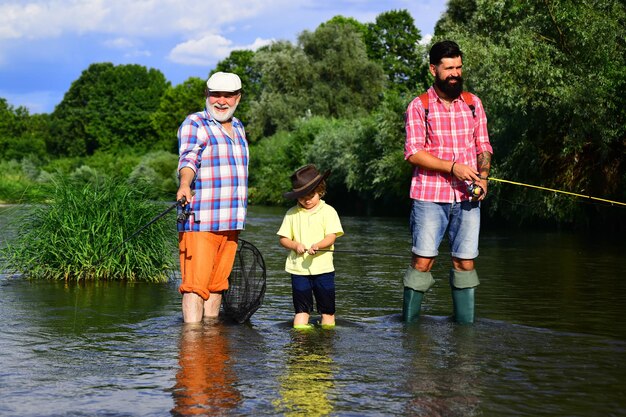 Grandfather father and grandson fishing together Grandson with father and grandfather fishing by lak