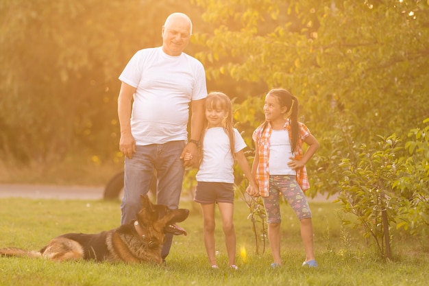 Grandfather And Granddaughters Taking Dog For Walk