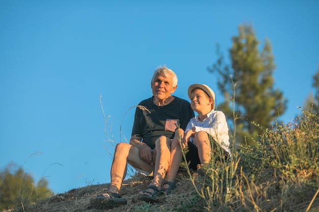 Grandfather and grandson enjoying outdoor smiling and hugging Concept of friendly family