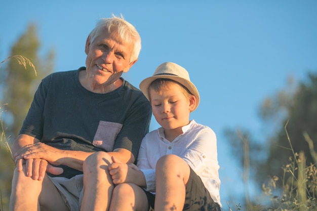 Grandfather and grandson enjoying outdoor smiling and hugging Concept of friendly family