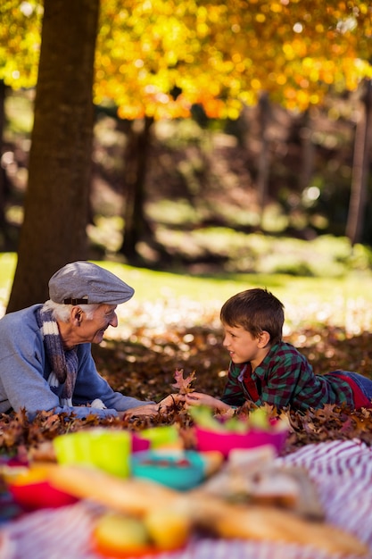 Grandfather and grandson lying on field during autumn