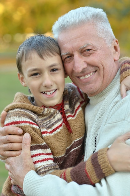 Grandfather and grandson together in autumn park