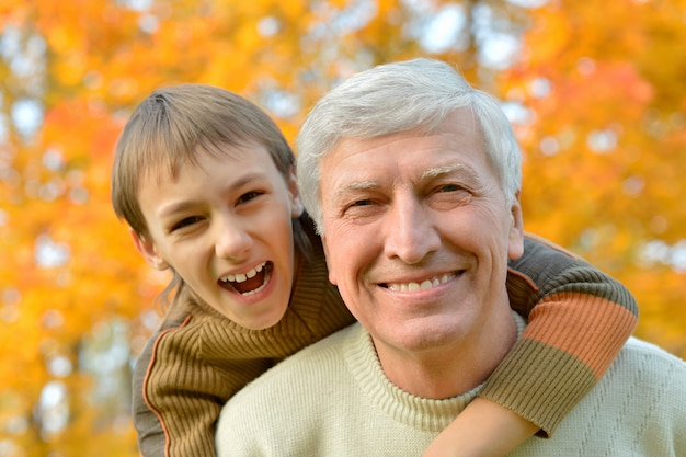 Grandfather and grandson together in autumn park