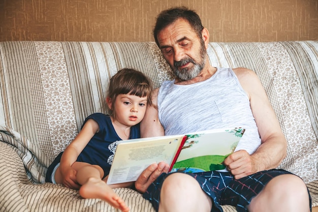 Grandfather reading a book to his granddaughter