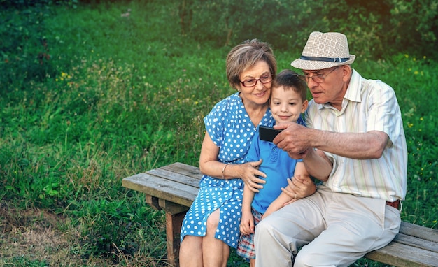 Grandfather taking selfie with grandmother and grandson sitting on a bench