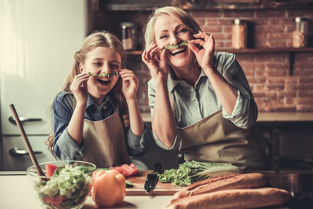 Grandma and granddaughter are making moustache.