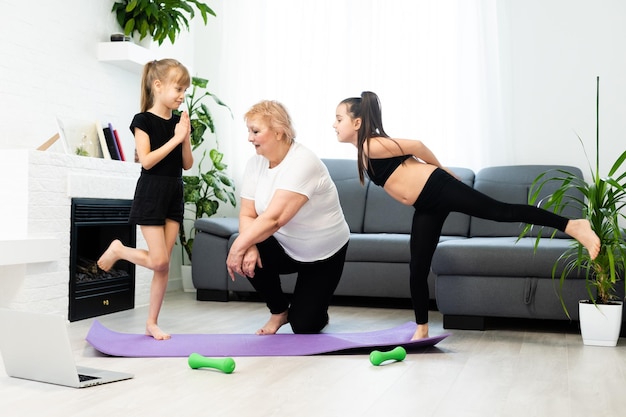 grandmother and children exercising workout at home near the window in room.