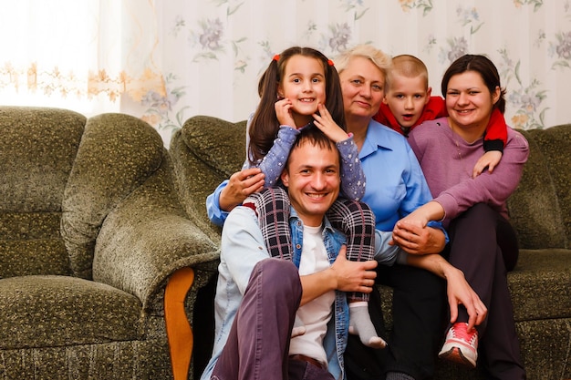 Grandmother and grandchildren sitting together on sofa in living room