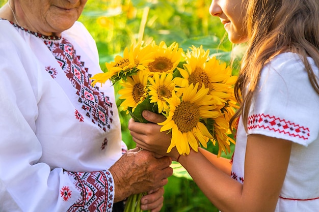 Photo grandmother and grandchildren in a sunflower field wearing an embroidered shirt selective focus