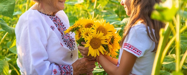 Photo grandmother and grandchildren in a sunflower field wearing an embroidered shirt selective focus