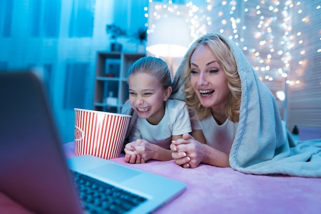 Grandmother and granddaughter are watching movie on laptop.