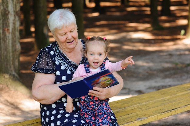 Grandmother and granddaughter reading the book in the park