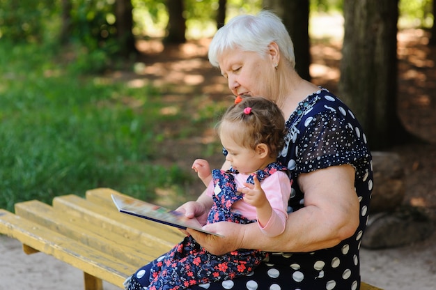 Grandmother and granddaughter reading the book in the park