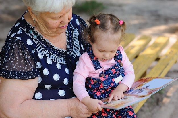 Grandmother and granddaughter reading the book in the park