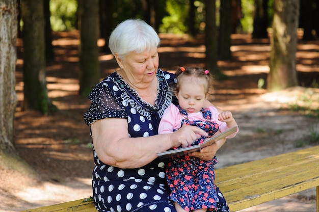 Grandmother and granddaughter reading the book in the park