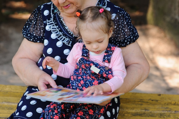 Grandmother and granddaughter reading the book in the park