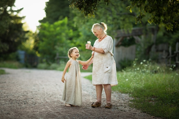 Grandmother and granddaughter walk around the park in white vintage clothes