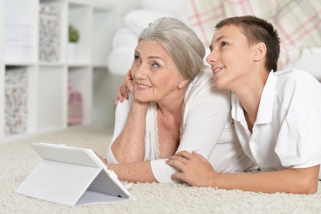 Grandmother and grandson lying on floor with tablet