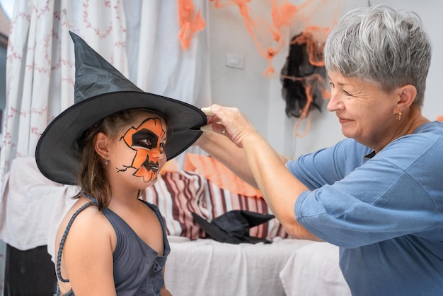 Photo grandmother helps a girl with a halloween costume