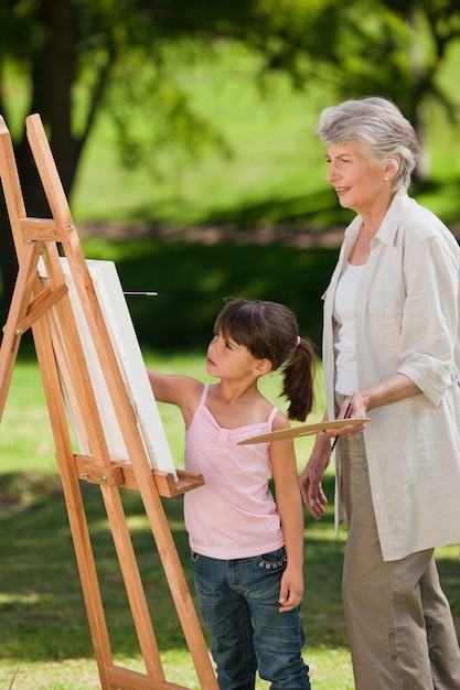 Grandmother and her granddaughter painting in the garden