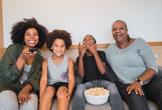 Grandmother, mother and children watching a movie at home.