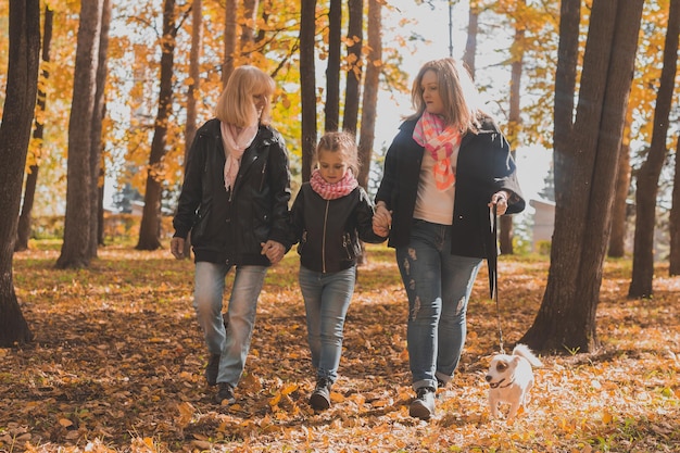 Grandmother and mother with granddaughter walks together in autumn park and having fun generation le