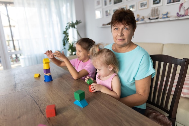 Grandmother playing at the table with her grandchildren at home