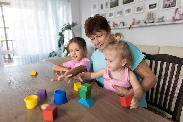 Grandmother playing at the table with her grandchildren at home