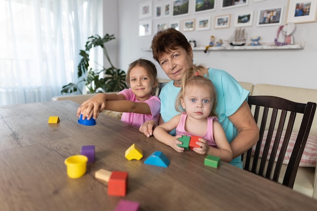 Grandmother playing at the table with her grandchildren at home