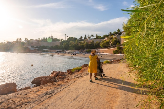 Grandmother walking with her grandson on the Caleta beach in the tourist town of Cabo Roig Alicante