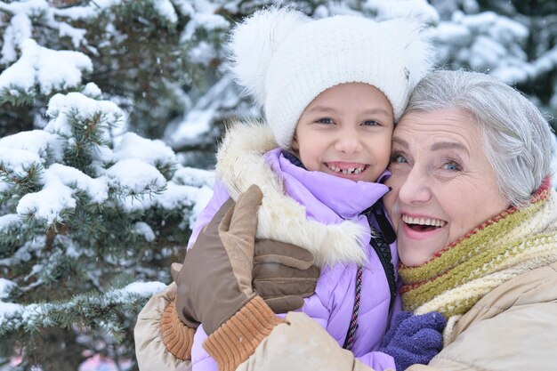 Grandmother with granddaughter smiling, posing outdoors in winter