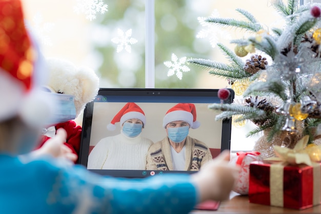 Grandpa and grandma greeting in video chat Laptop on windowsill against Christmas tree decoration