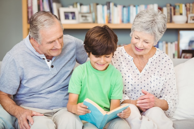 Grandparents assisting grandson while reading book