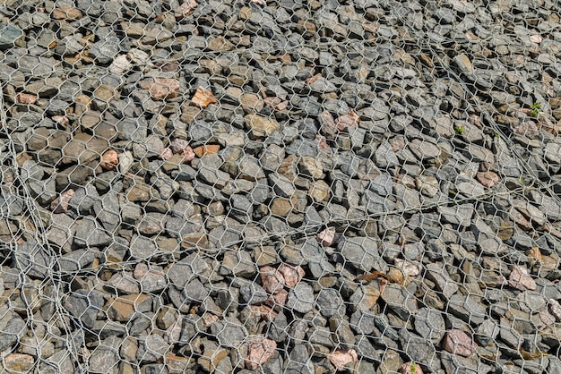 Granite gravel reinforcement of road embankment covered wth steel mesh fullframe background