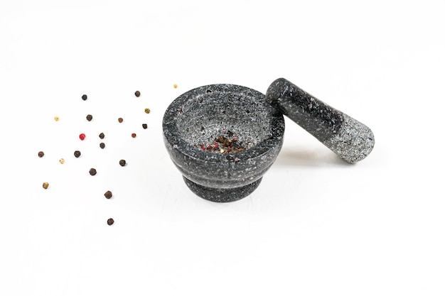 Granite gray mortar with pestle on a white background with pepper Stone mortar is an important tool in cooking pepper food