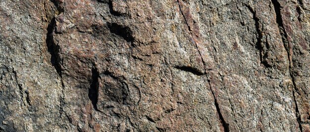 Granite rock texture. Cracked granite surface from weathering. Close-up of stone surface. Earth color concept