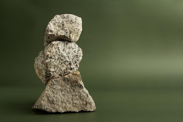 Granite stones stacked on a green background with copy space