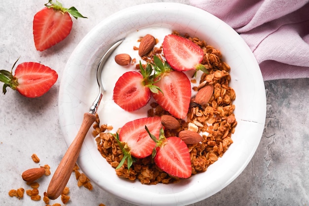 Granola Bowl of homemade granola with yogurt and fresh berries strawberry for breakfast in a white bowl on old gray concrete background table background Top view flat lay background