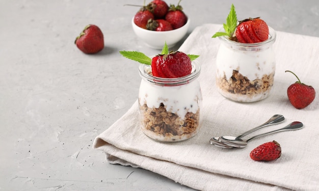 Granola crispy honey muesli with strawberry and natural yogurt, a delicious and healthy breakfast in glass jars