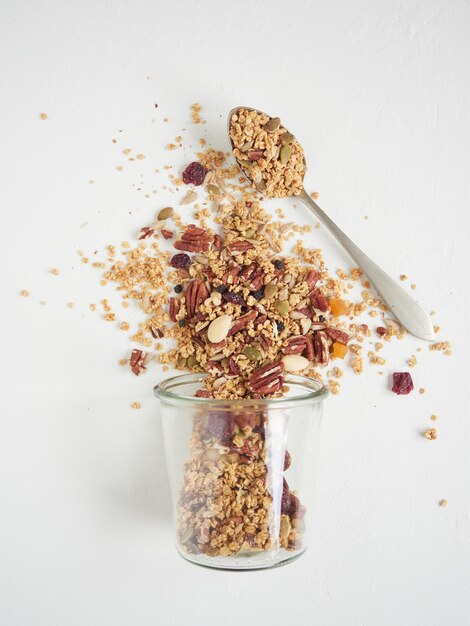 Photo granola spilled from glass near spoon