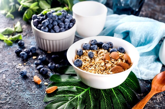 Granola with blueberries in white plate and cup of tea for breakfast, Homemade baked muesli with nuts and honey for little sweetness.