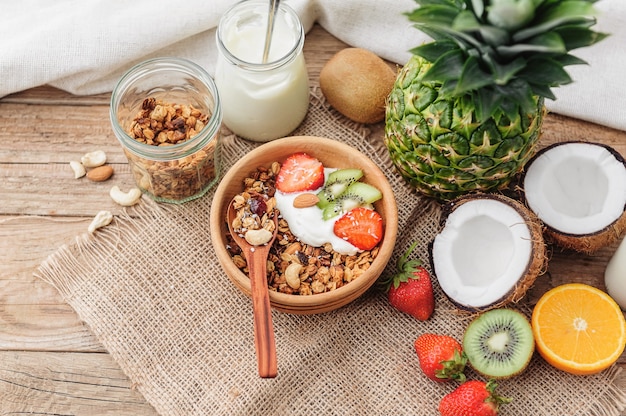 Granola with Greek yoghurt and fruit on a wooden background in a rustic style