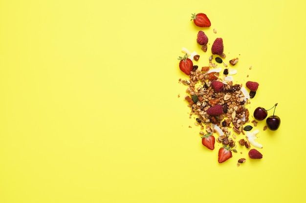 Granola with nuts and berries on a yellow background View from above