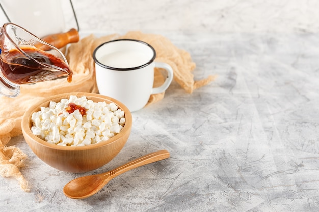 Granulated cottage cheese in wooden bowl and mug of milk